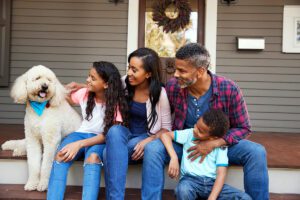 family with children and pet dog sit on steps of PC6VP9N