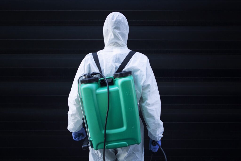 man white protective suit with reservoir spraying disinfection